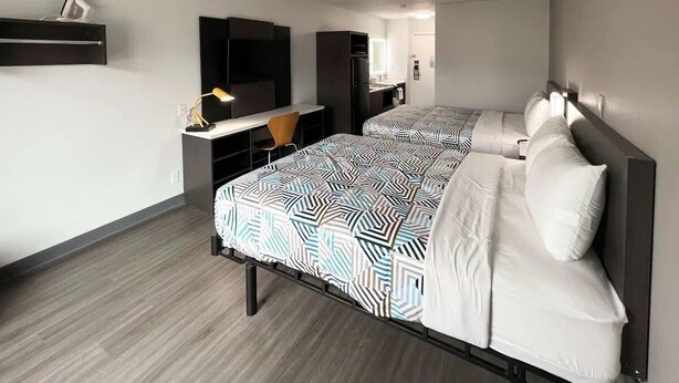 Une chambre d’hôtel avec deux lits, un bureau, une chaise, une télévision et un miroir.