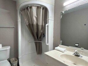 Ein Badezimmer mit Dusche, Toilette, Waschbecken und Spiegel.