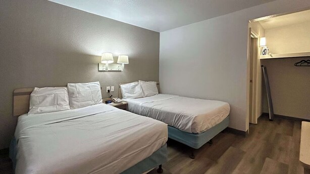 A hotel room with two beds, a nightstand with a phone, and a coat rack. - Enjoy a Convenient Kitchen-Equipped Stay for Longer Comfort | Free Parking (Lubbock)