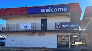 A building with a 'welcome' sign, a 'NOW OPEN' sign, and a '6' sign. - Enjoy a Convenient Kitchen-Equipped Stay for Longer Comfort | Free Parking (Lubbock)