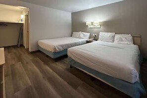 Ein Hotelzimmer mit zwei Betten, einem Schreibtisch und einem Kleiderschrank.