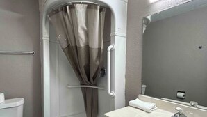 Une salle de bain équipée d’une douche, de toilettes, d’un lavabo et d’un miroir.