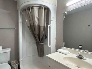 Ein Badezimmer mit Dusche, Toilette, Waschbecken und Spiegel.