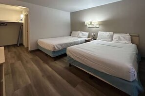 Ein Hotelzimmer mit zwei Betten, einem Schreibtisch und einem Kleiderschrank.