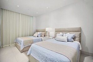 A hotel room with two beds, a nightstand, a lamp, and a window with curtains. - Amazing Four Seasons Beachfront 4BR Residence - Golf Cart Included (Río Grande)