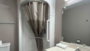 Un bagno con doccia, WC, lavandino e specchio.