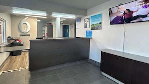 A reception area with a counter, a TV mounted on the wall, and a number '6' sign. - Pet-Friendly Getaway + Free Parking Near Buddy Holly Center - 4.1 miles (Lubbock)