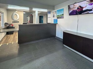 Ein Empfangsbereich mit einer Rezeption, einem an der Wand befestigten Fernseher und einem Schild mit der Nummer 6.