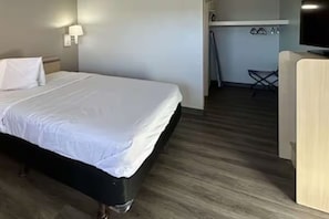 Habitació d'hotel amb un llit, una taula de treball, una televisió i una cuineta petita.