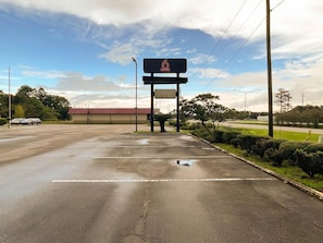 Ein Parkplatz mit einem Tankstellenschild, ein Gebäude mit rotem Dach und einem wolkenlosen Himmel.