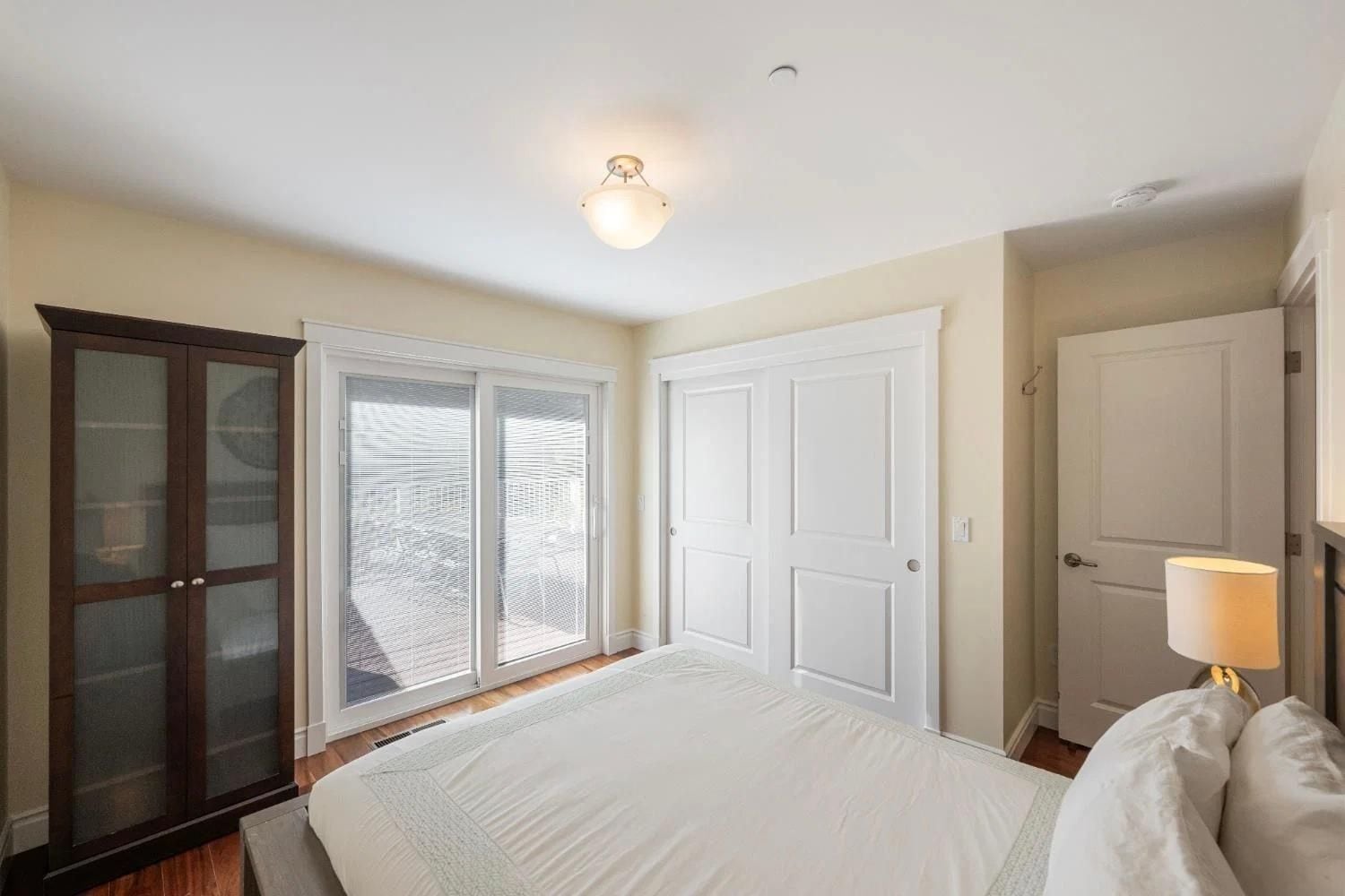 A bedroom with a bed, a wardrobe, a door, and a ceiling light.