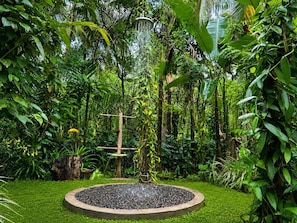 A circular water feature surrounded by lush greenery and a wooden structure.