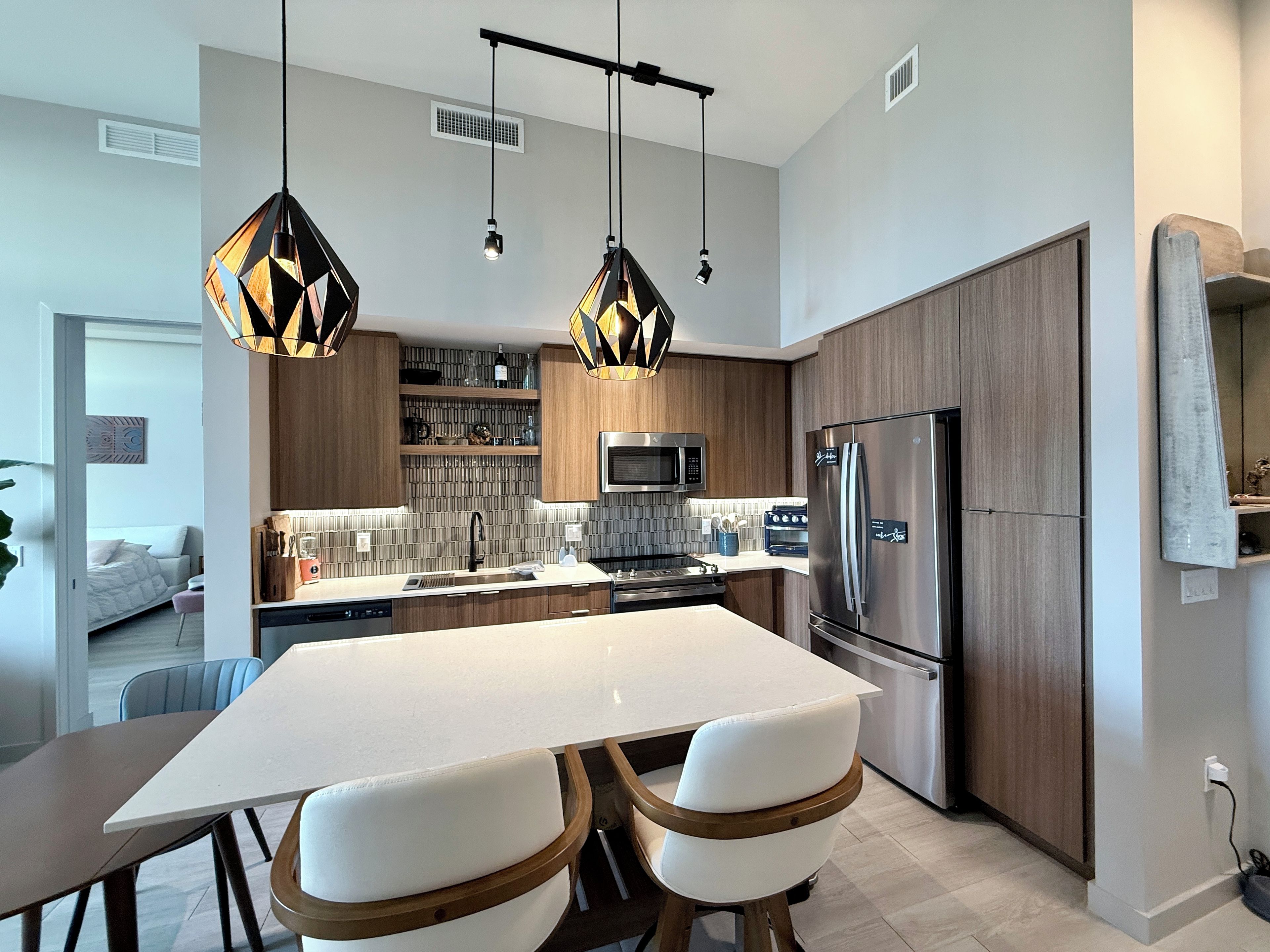 A modern kitchen with a central island, stainless steel appliances, and pendant lighting.