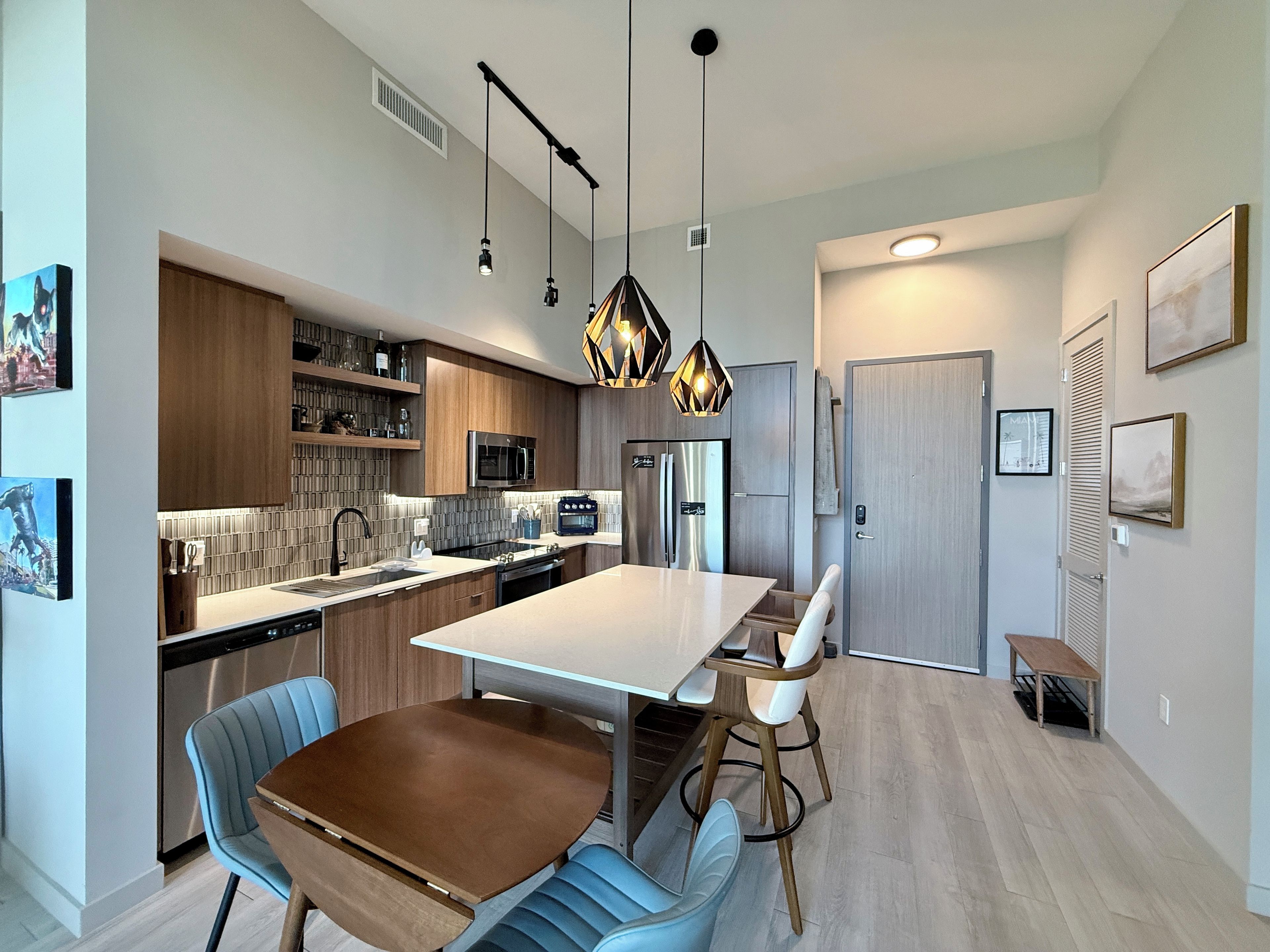 A modern kitchen with a central island, stainless steel appliances, and pendant lighting.