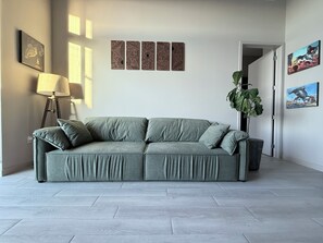 A living room with a grey sofa, a floor lamp, and wall art. - Luxury 2BR Retreat in Flagler Village / Private Terrace + King Bed (Fort Lauderdale)