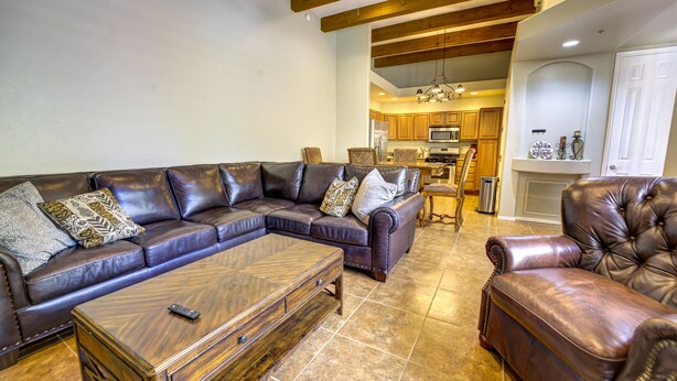 A living room with a sectional sofa, a leather armchair, and a wooden coffee table. - Cozy 2-bedroom condo with AC in serene Tubac (Tubac)