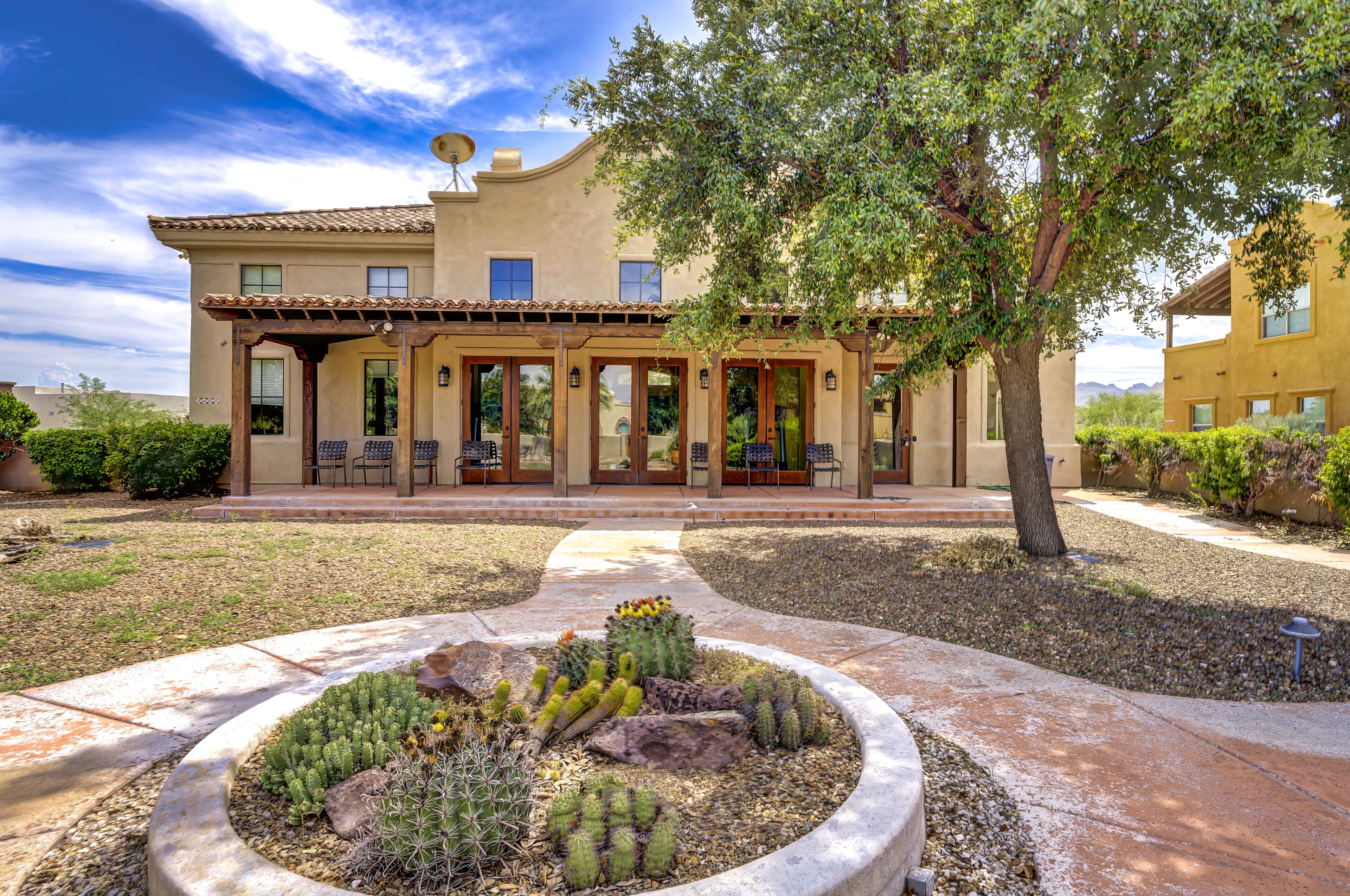 A two-story building with a patio area, outdoor seating, and a cactus garden.