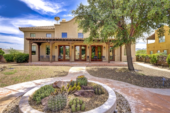 A two-story building with a patio area, outdoor seating, and a cactus garden.