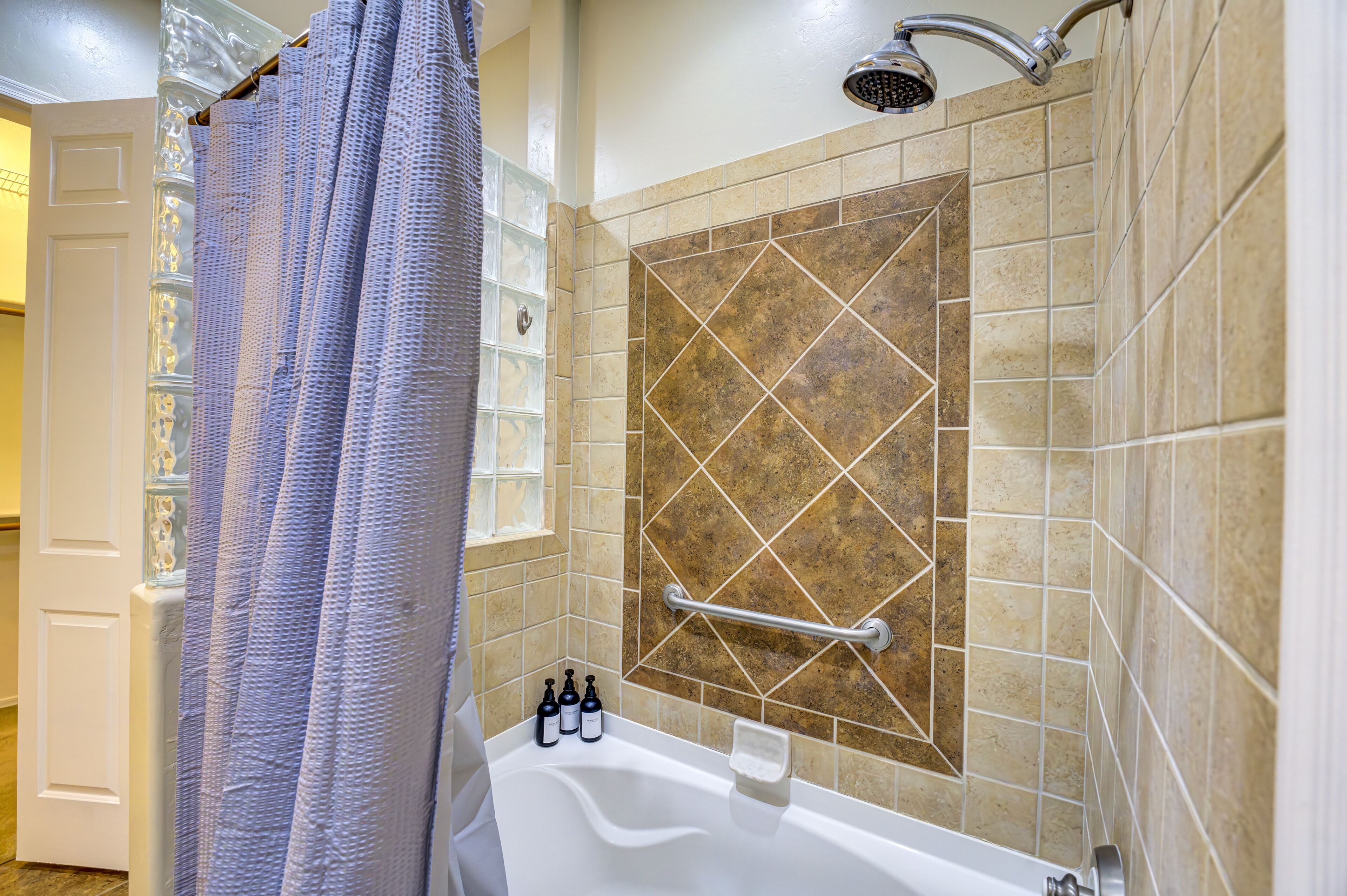 Une salle de bain avec une baignoire, une douche et un mur recouvert de carreaux disposés en motif losange.