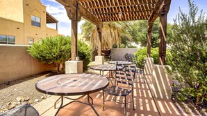 An outdoor patio with tables and chairs, a pergola, and a building in the background. - Cozy 2-bedroom condo with AC in serene Tubac (Tubac)