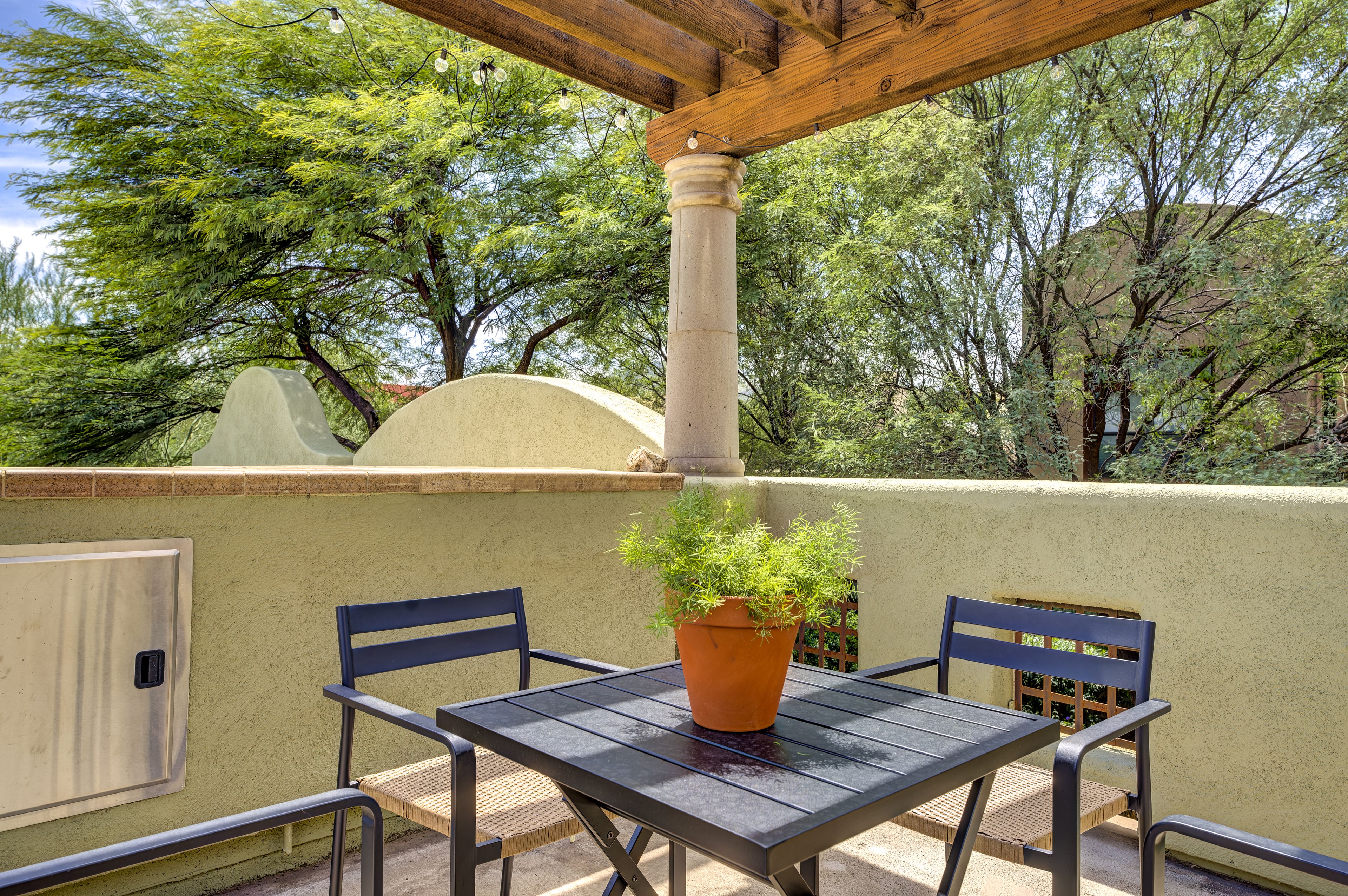 Eine Außenpatio mit Tisch, Stühlen, einem Topfpflanzen und einer Pergola.