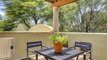 Eine Außenpatio mit Tisch, Stühlen, einem Topfpflanzen und einer Pergola.