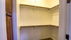 Een hoekkast met witte wanden, houten deuren en metalen schapunits.