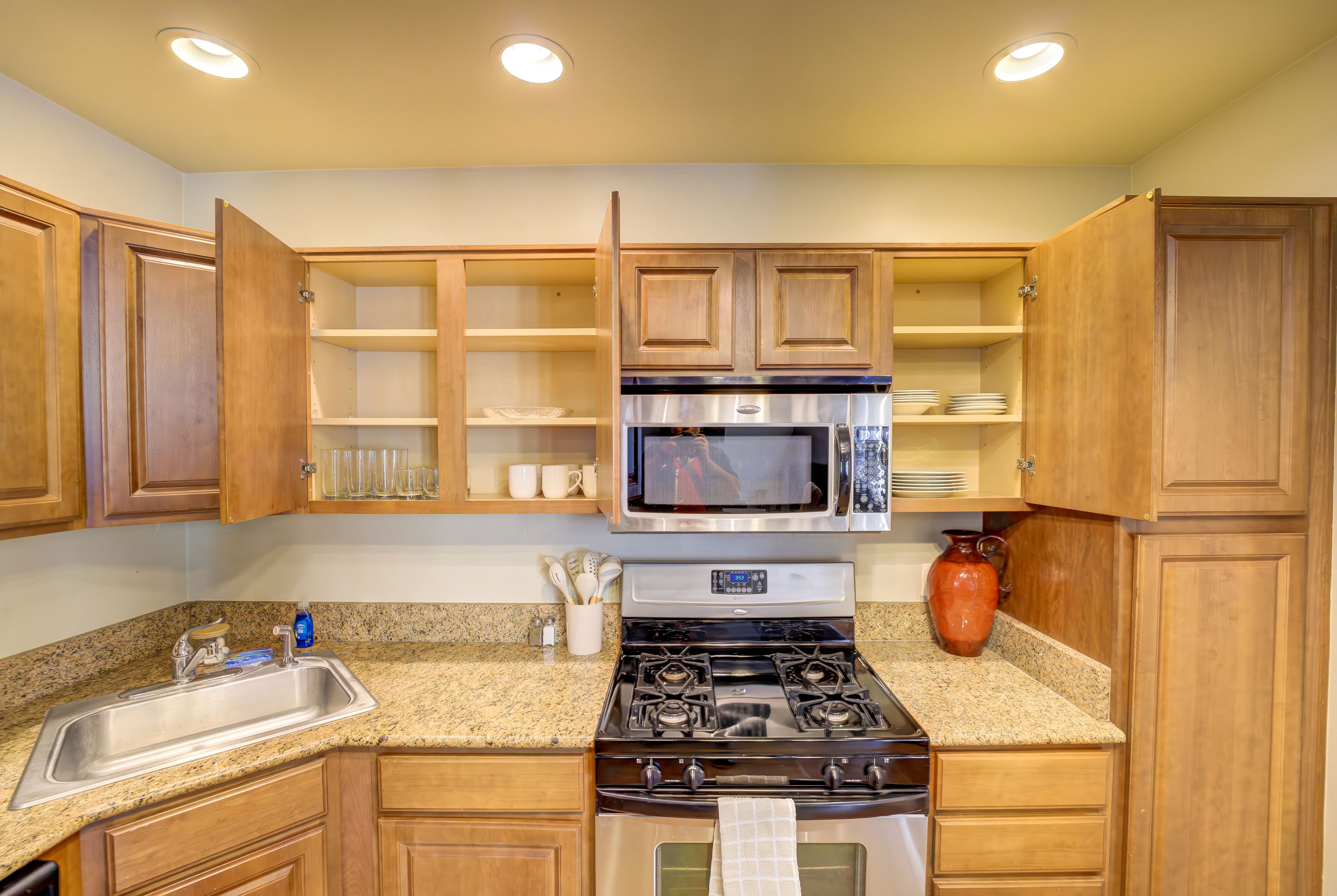 A kitchen with wooden cabinets, a stainless steel stove, a microwave, and a granite countertop.