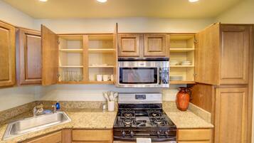 A kitchen with wooden cabinets, a stainless steel stove, a microwave, and a granite countertop.