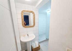 A bathroom with a white sink, a mirror with a woven frame, and a glass shower enclosure. - Corales Ducassi Rooftop pool & tropical Caribbean sun (Punta Cana)
