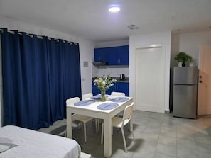 A compact room with a dining table, chairs, a bed, a kitchenette, and a door. - Corales Ducassi Rooftop pool & tropical Caribbean sun (Punta Cana)