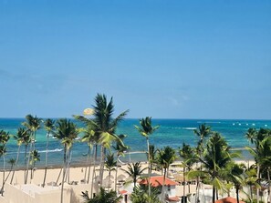 Blick auf einen Strand mit Palmen und blauem Himmel.