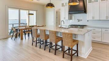 A modern kitchen with white cabinets, a central island, and a view of the water.