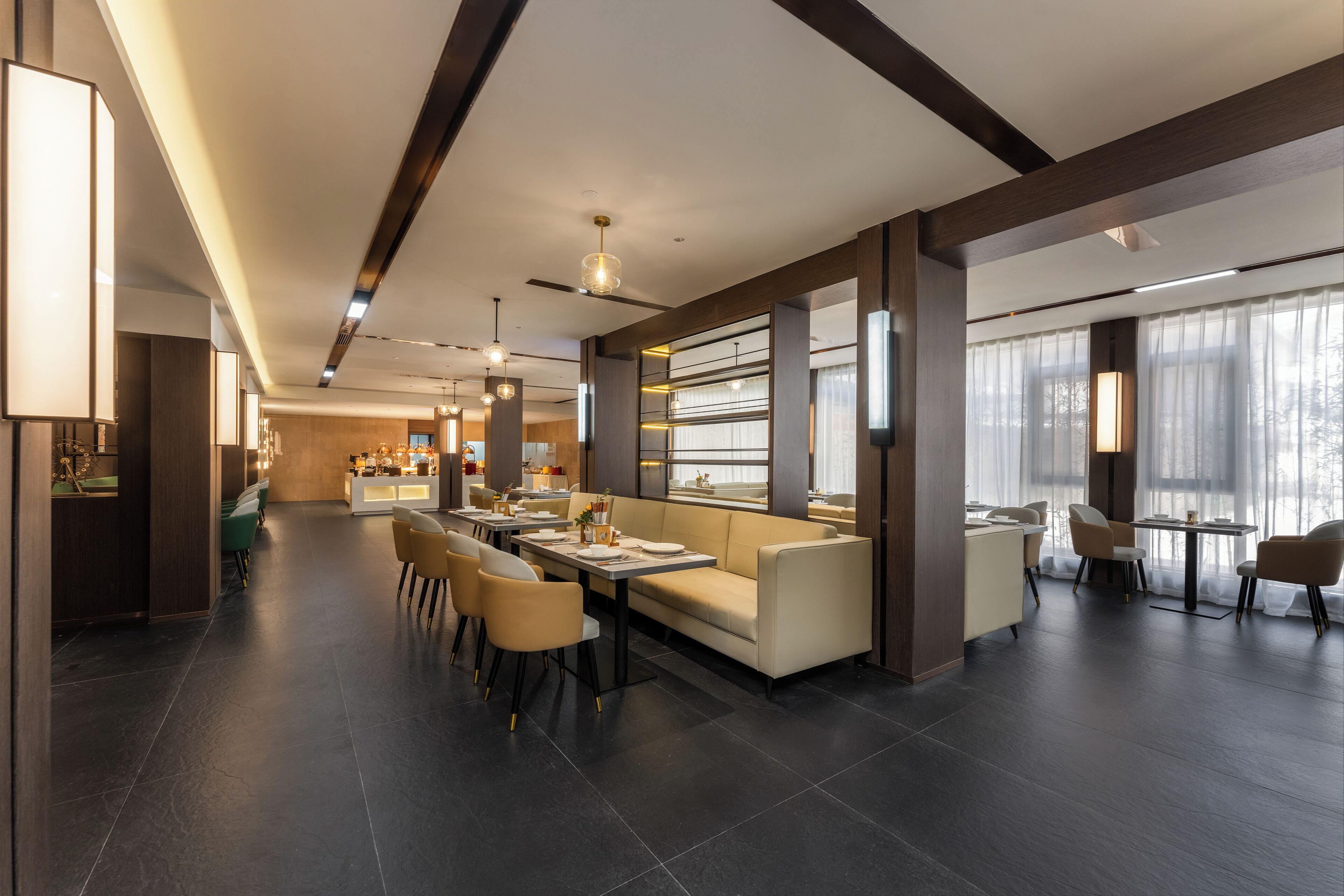 Um saguão de hotel moderno, com área de estar central, bar e balcão de recepção.