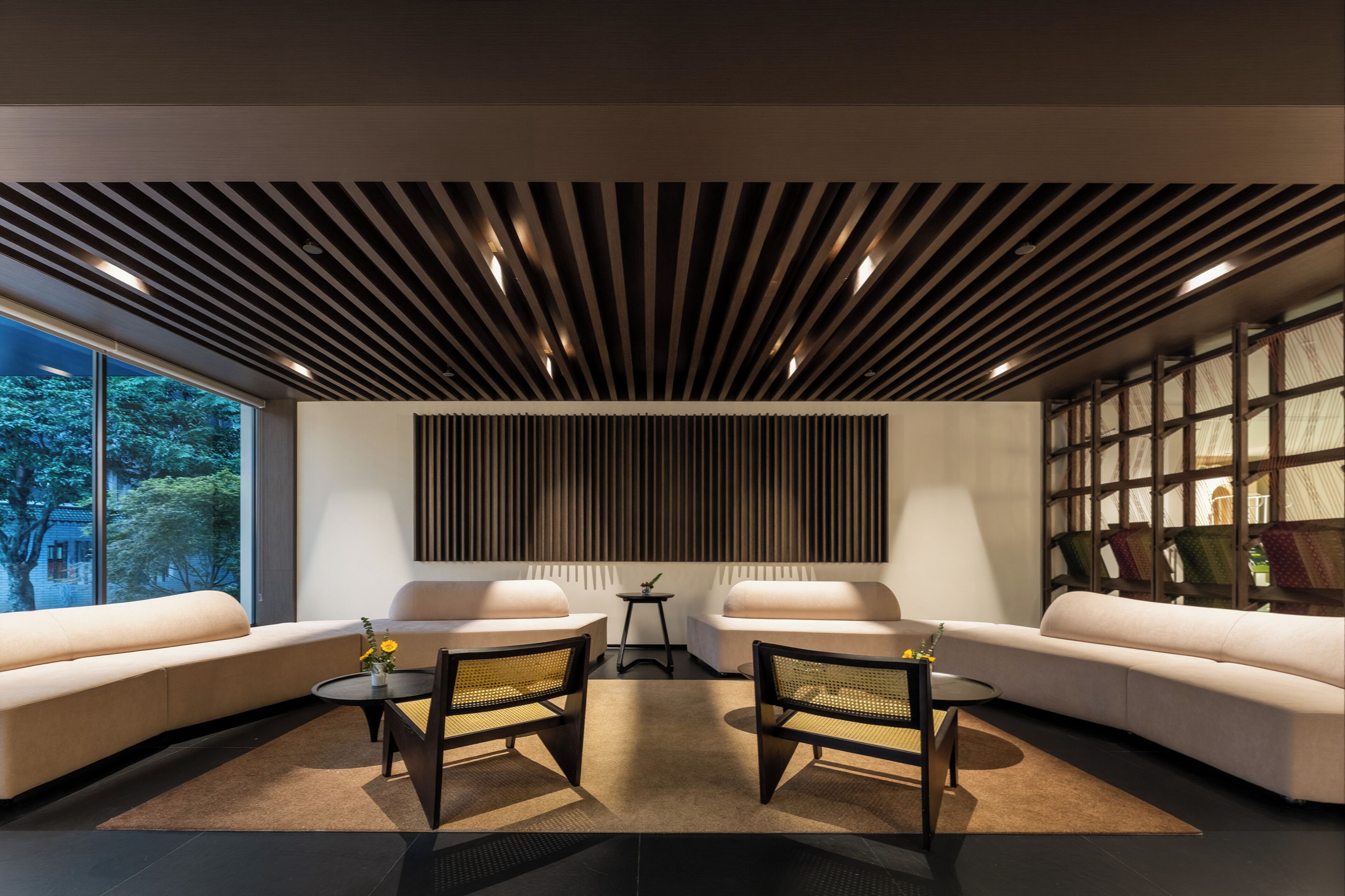 Un interior moderno con un sofá modular, dos sillones, una mesita y un panel decorativo en la pared.
