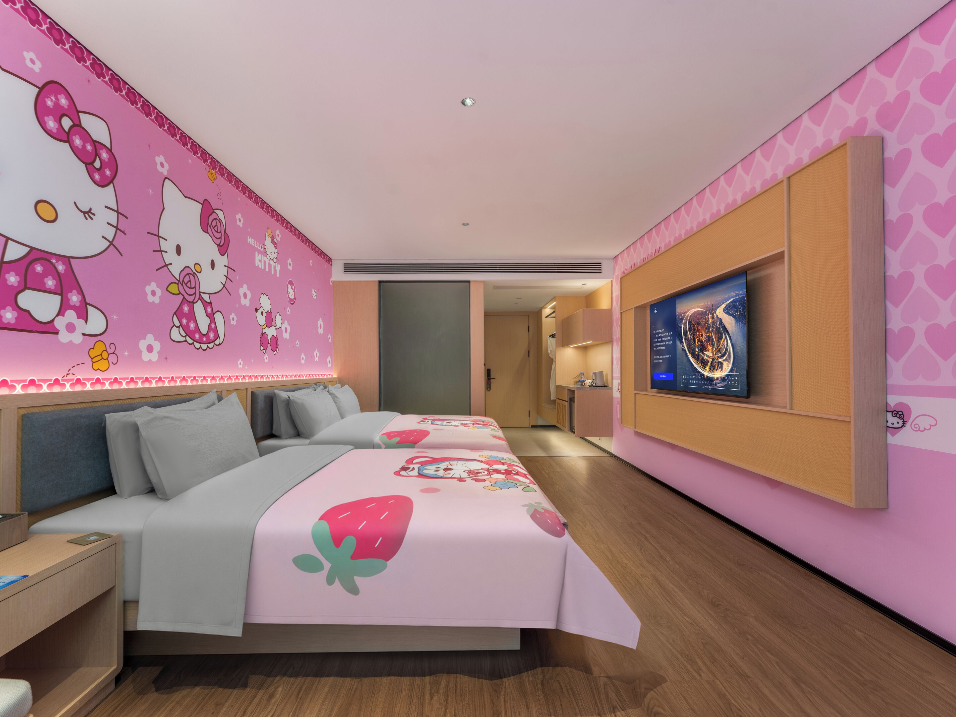 Una habitación de hotel con una pared rosa, una cama con diseño de Hello Kitty, un televisor en la pared y suelo de madera.