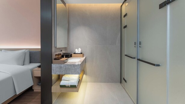 A modern bathroom with a built-in vanity, a large mirror, and a walk-in shower. - Ting Ran Yun Ju Hotel Guilin (Nanjing)