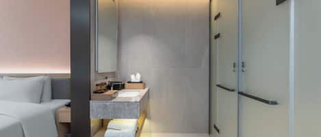 A modern bathroom with a built-in vanity, a large mirror, and a walk-in shower.