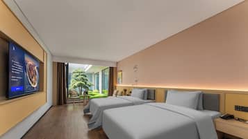 A hotel room with two beds, a television, a small table, and a view of a garden.