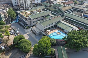 Um edifício com vários andares, piscina no terraço e área externa coberta.