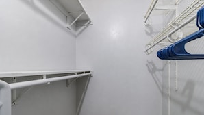 Een hoek van een kamer met een witte muur, een wit plafond en een witte vloer. Tegen de muur staat een witte plankkast en er loopt een witte pijp langs het plafond.