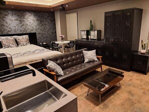 Ein modernes Hotelzimmer mit Bett, Sofa, Couchtisch und einer Küchenzeile.