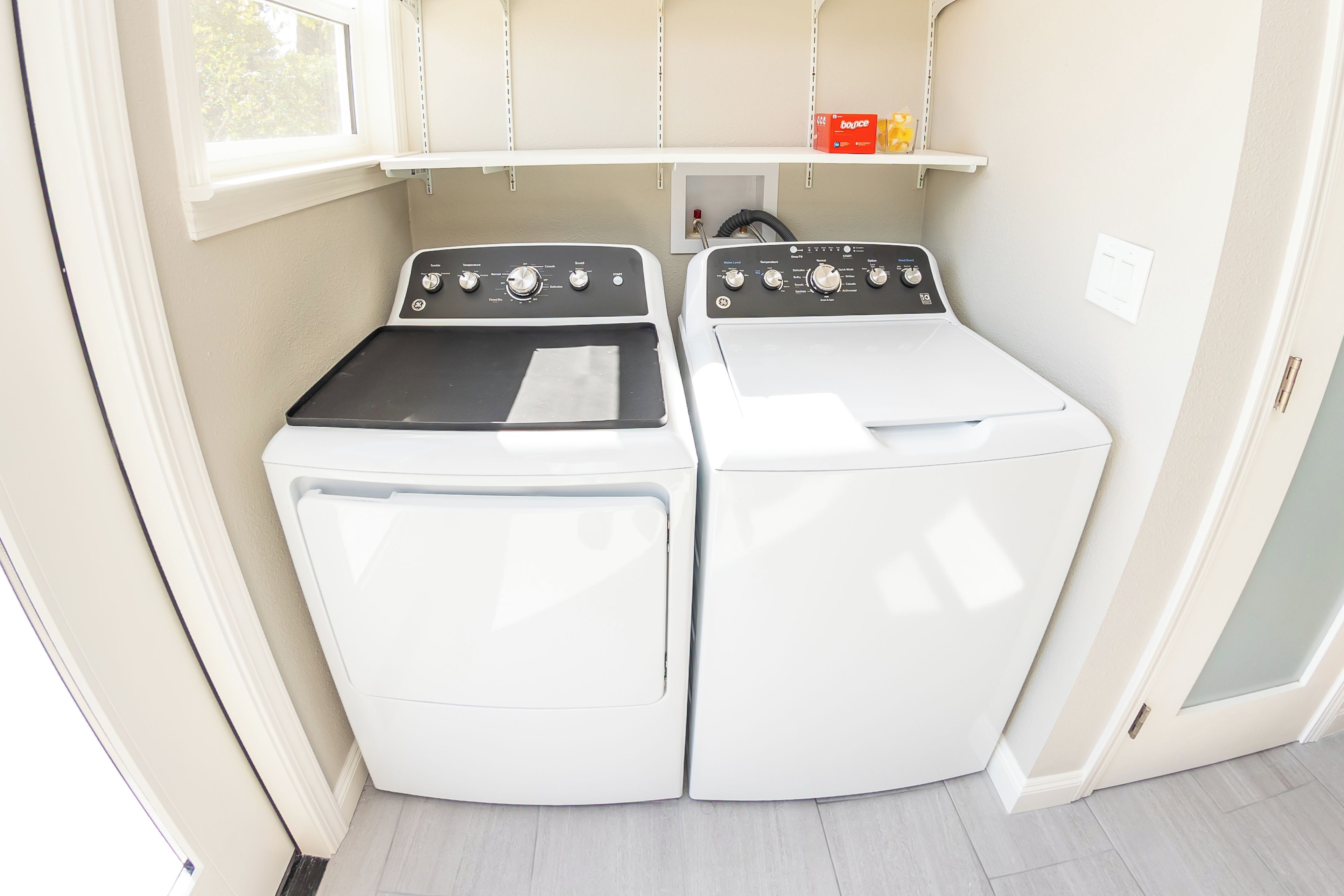 A compact laundry room with two white washing machines and a shelf above them.