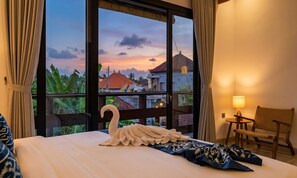 Quarto de hotel com uma janela grande, uma cama com travesseiro em formato de cisne, uma cadeira e um abajur.