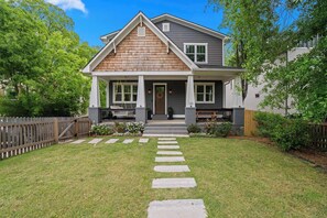 A two-story house with a front porch, a wooden deck, and a well-maintained lawn. - NEW Luxe 7BR Sleeps 20 - Hot Tub - 13 Min Downtown (Atlanta)