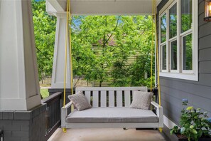 A porch with a swing seat, a white railing, and a window. - NEW Luxe 7BR Sleeps 20 - Hot Tub - 13 Min Downtown (Atlanta)