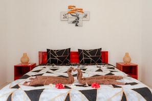 A bed with a geometric patterned bedspread, two pillows with a geometric design, and a wall art piece above the bed.