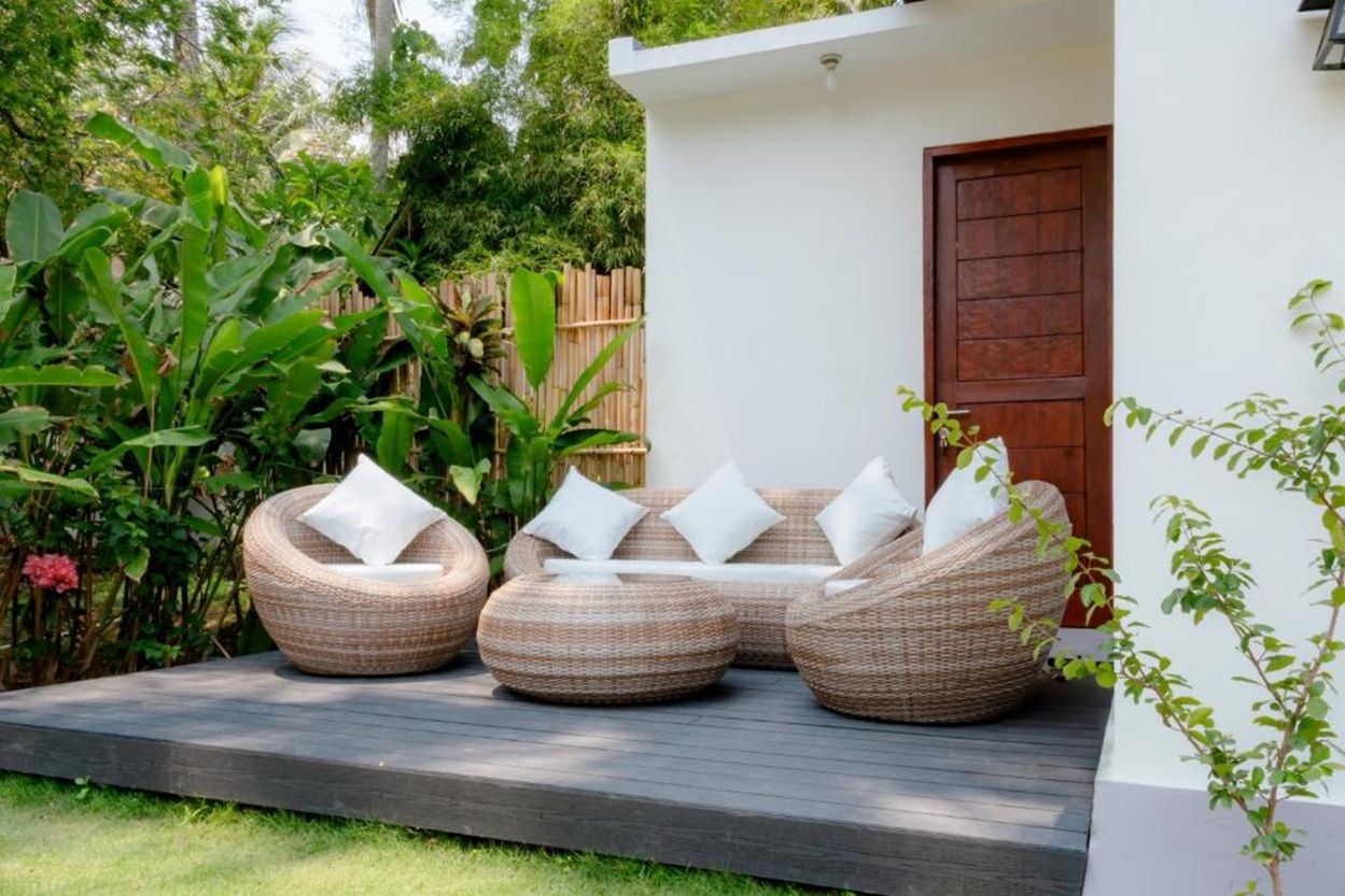 A garden with wicker furniture and a wooden door.