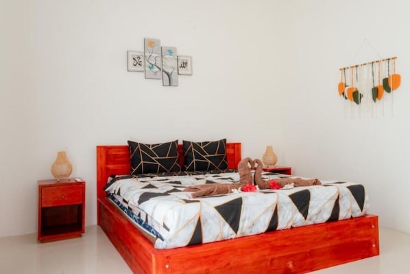 A neatly made bed with a geometric patterned bedspread, a wooden headboard, and two pillows.