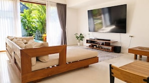 A modern living room with a sofa, TV, and a dining area.